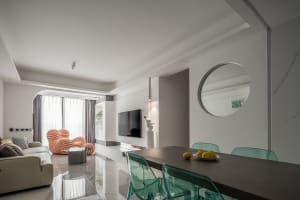 A modern living room with white marble flooring, a beige sofa, and green plastic chairs.
