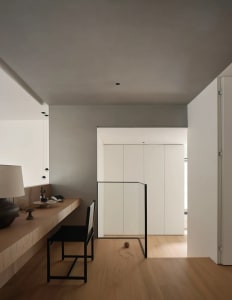 A minimalist residential interior featuring light wood, glass, and metal elements.