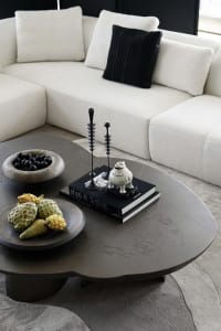 A modern living room with a large sectional sofa, a unique concrete coffee table, and decorative elements such as a fruit bow