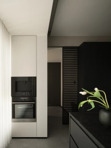 Modern minimalist kitchen featuring dark grey and black materials, concrete countertops, and sleek black appliances.