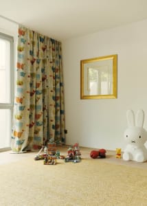 A children's room with playful decor, including colorful curtains, toys, and a large rabbit sculpture.