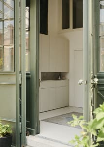 A modern apartment entryway featuring white walls, doors, and cabinets.