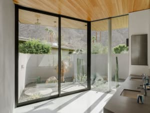 Modern bathroom featuring a minimalist design with concrete walls, a glass shower enclosure, and a wooden ceiling.