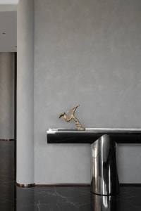 A sleek, modern console table with a brass sculpture in a minimalist interior setting.