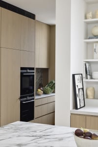 Modern kitchen with wooden cabinets and marble countertop featuring minimalist design elements.