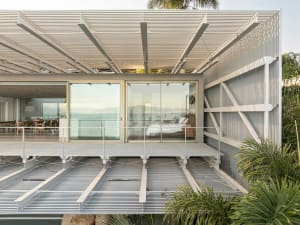 Contemporary residential home featuring metallic structures and large glass windows overlooking the sea.