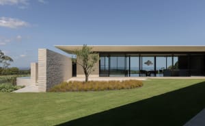 A modern house with glass walls, brick walls, and concrete patio.