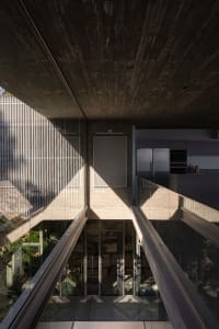 A futuristic industrial-style residential kitchen designed with concrete and glass materials, featuring a sleek, modern aesth