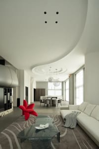Modern living room with minimalist design, featuring concrete flooring and sleek, white furniture.