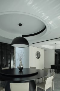 Modern minimalist dining room with black table, chairs, and metallic vase.