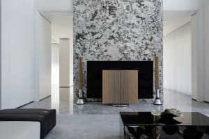 A minimalist living room with marble walls and a black coffee table.