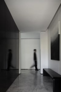 A modern hallway with minimalist design, featuring sleek black and white color scheme and a combination of concrete and glass