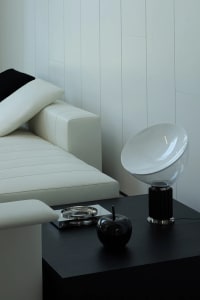 A modern interior design featuring a white leather sofa with black throw pillows, accompanied by a black and white table lamp
