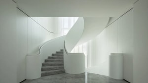 Modern staircase featuring white marble steps and white concrete walls.