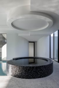 A modern minimalist spa interior featuring a circular tiled spa