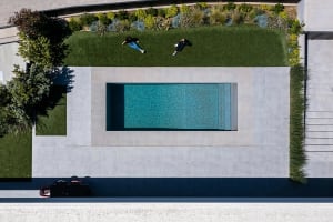 Modern residential home featuring a concrete swimming pool surrounded by greenery and grass.