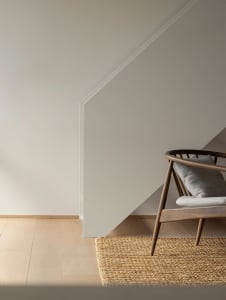 A minimalist living room featuring neutral-toned furniture and a wooden floor with a textured rug.