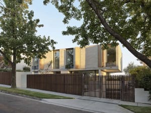 Modern residential exterior featuring stone façade, large windows, and lush greenery.