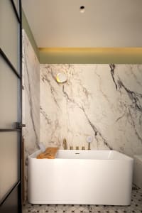 Modern bathroom interior with white marble walls and a freestanding bathtub.