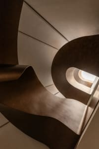 A modern, metallic staircase with sleek, curved steps and a minimalist design.