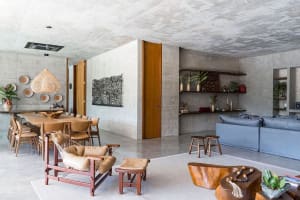 A spacious, modern industrial living room with concrete walls and floors, featuring a blue sofa and wooden furniture.