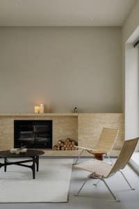 A minimalist living room with a stone fireplace, candles, and chairs.