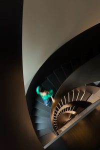 A person climbing a modern, curved staircase made of metal.