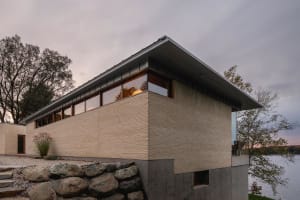 Modern building made of brick with large windows overlooking a body of water.