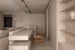 A minimalist house's concrete interior featuring a sleek, modern kitchen and living area with warm wooden accents.