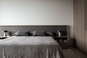 A minimalist bedroom with a gray fabric bedspread and matching pillows.