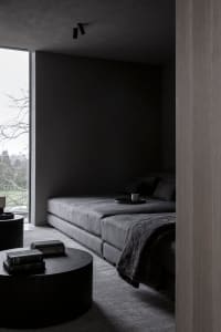A modern minimalist living room with a large sofa, coffee tables, and a window view of nature.