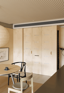 A modern minimalist kitchen with wooden cabinets and a dining table.