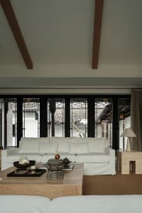 White sofa in a living room with wooden beams on the ceiling and traditional Chinese-style windows, featuring a wooden coffee