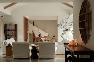 A living room with white and wooden furniture. Multiple seating options, a low coffee table, and a side table adorned with ca
