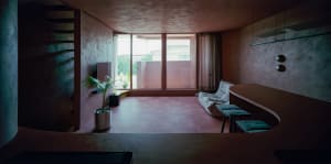 A modern living room with concrete flooring and walls, featuring a lounge area and a bar counter.