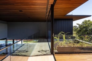 Modern residential interior featuring wood flooring and large windows with a view of greenery.