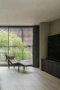 A modern living room with a lounge chair, large window, and wooden flooring.