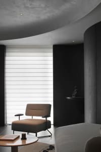 Modern living room with black walls, minimalist design, and white window blinds.
