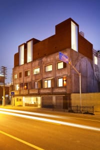 A modern residential building with concrete walls and large windows in an urban setting.