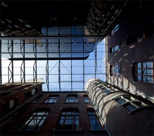 A modern industrial building with brick walls and glass panels, viewed from below.
