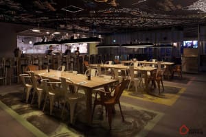 Industrial-themed restaurant with wooden tables and contemporary light fixtures.