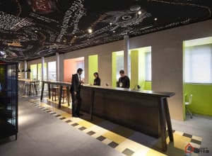 A minimalistic coffee shop with a modern metal counter, glass windows, and concrete flooring.