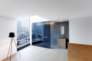 A modern living room with a waterfront view, featuring concrete and glass materials.