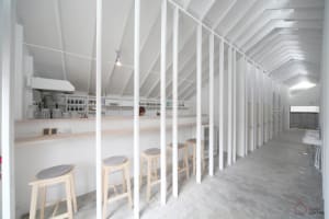 A minimalist cafe bar interior with concrete floors and white walls.