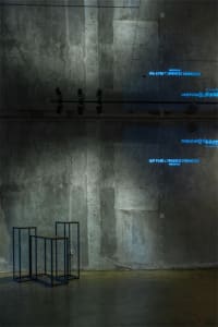 A minimalist industrial installation with concrete walls and an abstract metal structure.