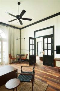 A stylish, industrial-themed living room with wooden flooring, black-framed windows, and a minimalistic design.