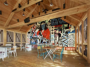 Urban-themed cafe interior with wooden floors, white chairs, and colorful artwork on the walls.