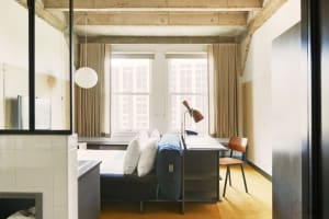 A minimalist bedroom featuring concrete, wood, and fabric materials.
