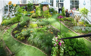 A vibrant, modern garden with green space and various plants and decor.