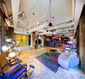 Industrially styled modern lobby featuring exposed concrete, glass walls, and wooden furniture.